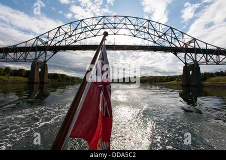 Un yacht à voile avec un drapeau britannique passe le pont Bourne dans le canal de Cape Cod dans le Massachusetts USA Banque D'Images