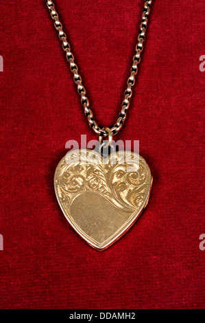 Pendentif en forme de coeur d'or sur un fond noir. Banque D'Images