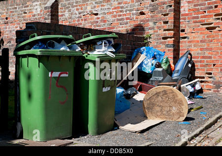 Plein débordement ménager vert déchets poubelles à roulettes poubelle et mouche basculant Tipped ordbish mess Angleterre Royaume-Uni GB Grande-Bretagne Banque D'Images