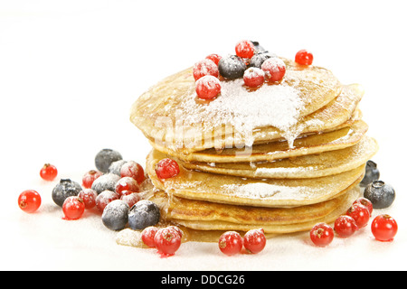 Petites crêpes garnies de myrtilles et groseilles rouges sur fond blanc Banque D'Images