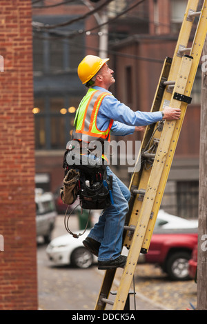 Poseur de câbles sur une échelle d'escalade sur city building Banque D'Images