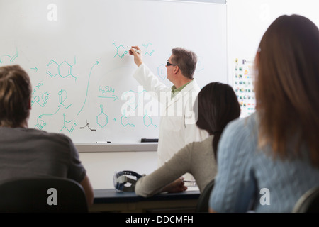 Les élèves assis dans une salle de classe d'ingénierie à écouter le professeur parler de liens chimiques anneaux de benzène Banque D'Images