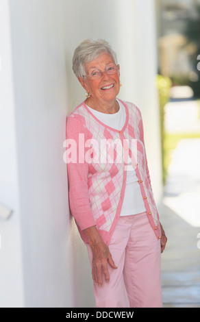 Senior woman smiling appuyé contre un mur Banque D'Images