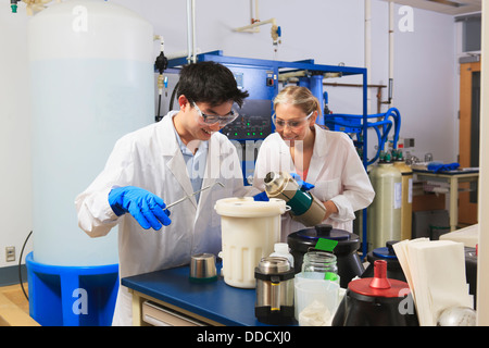 Les étudiants en ingénierie à l'aide de forceps en maintenant l'azote liquide Dewar ballon dans la salle de traitement de l'eau dans un laboratoire Banque D'Images