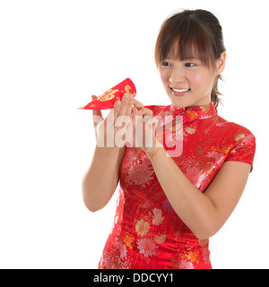 Femme Asiatique avec une robe traditionnelle chinoise ou qipao cheongsam holding ang pow don en argent, oeil rouge en paquet. Le nouvel an chinois Concept, modèle féminin isolé sur fond blanc. Banque D'Images