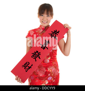 Femme Asiatique avec une robe traditionnelle chinoise ou qipao cheongsam holding couplet, le mot chinois signifie félicitations et meilleurs vœux pour une nouvelle année prospère. Modèle féminin isolé sur fond blanc. Banque D'Images