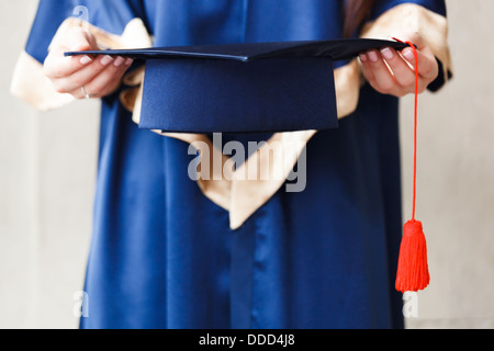 Jeune étudiant universitaire holding hat in hands Banque D'Images