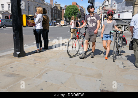 Londres, Angleterre, Royaume-Uni. Jeune couple poussant des vélos sur le trottoir dans Whitehall Banque D'Images
