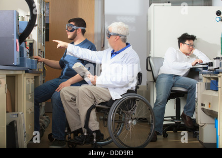 Le professeur avec la dystrophie musculaire et une étudiante en génie à l'aide de l'analyseur thermogravimétrique dans un laboratoire Banque D'Images