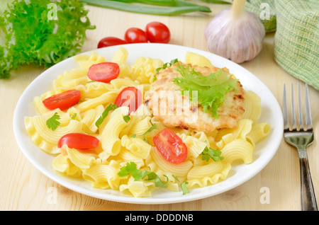 Pâtes aux tomates et poulet escalope sur plaque blanche sur la table en bois Banque D'Images