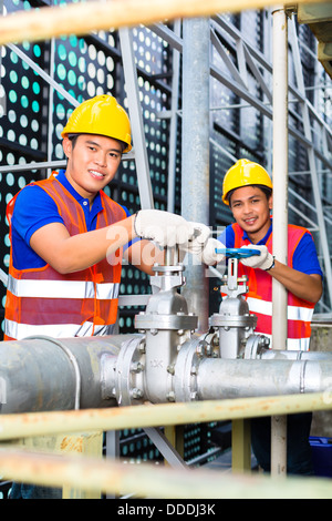 Deux techniciens ou ingénieurs travaillant sur une vanne sur la construction d'équipement technique ou site industriel Banque D'Images