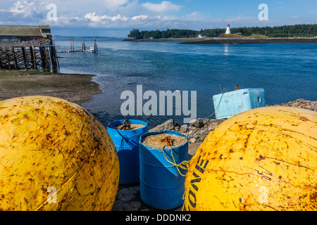 Une vue de Lubec, Maine mer avec une grande flotte de métal jaune au premier plan Mulholland Point Lighthouse en arrière-plan. Banque D'Images