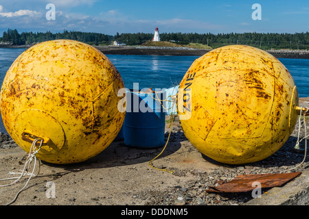 Une vue de Lubec, Maine mer avec une grande flotte de métal jaune au premier plan Mulholland Point Lighthouse en arrière-plan. Banque D'Images