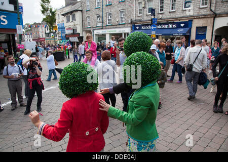 Couronne ronde, circulaire, verte, perruques artificielles à feuilles topiaires, jardinière portée par des artistes de rue à Kendal, Cumbria, Royaume-Uni. Août 2013. Mintfest, Kendal's International Festival of Street Arts, The Poheads byt's Circus, Outside Fat face Shop, un événement de week-end de Lakes Alive dans le Lake District qui a présenté quelques-uns des meilleurs du monde entier qui ont joué, danse contemporaine, cirque, comédie, musique, groupe original en plein air dans les rues. Banque D'Images