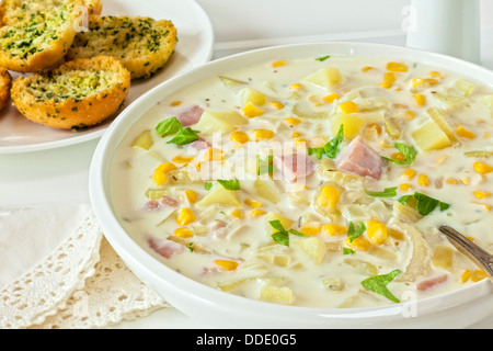 Chaudrée de maïs - Chaudrée de maïs crémeux au jambon et pommes de terre, servi avec du pain à l'ail croustillant. Banque D'Images