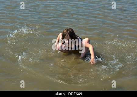 Parution du modèle de droit d'une jeune fille à jouer dans les vagues à Southend on Sea, Essex. Banque D'Images