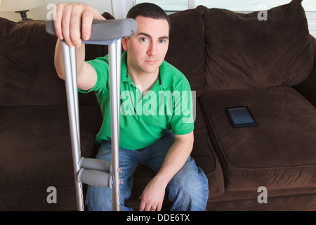 Après l'homme ligament croisé antérieur (LCA) avec des béquilles et une tablette numérique à la maison Banque D'Images