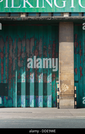 Ancien entrepôt de métal vert porte pliante avec peinture écaillée sur d'anciens locaux de Pilkington à Bristol Banque D'Images