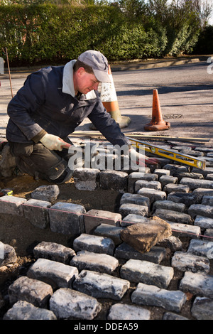 L bâtiment maison, disque de l'aménagement paysager, pose de pavés de granit récupérés workman à l'entrée du garage Banque D'Images