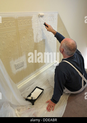 La décoration traditionnelle, peintre et décorateur peinture lincrusta nouvellement accroché dans les escaliers avec rouleau à peindre Banque D'Images