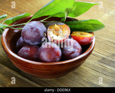 Les prunes violettes mûres sur une table en bois
