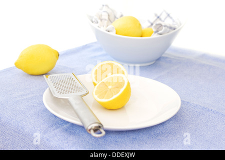 Citrons non ciré sur une plaque avec un citron zester, et un bol de citrons dans l'arrière-plan Banque D'Images