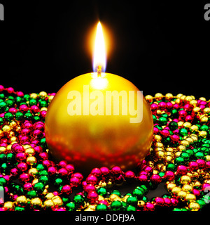Or ronde bougie de Noël assis en perles colorées sur un fond noir. Banque D'Images