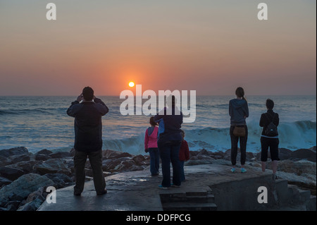 Une famille de montres et de photographies le coucher du soleil sur l'océan à Swakopmund, Namibie Banque D'Images