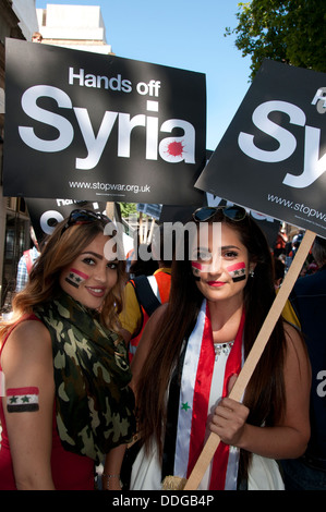 Manifestation contre toute intervention en Syrie.Deux jeunes femmes ont des drapeaux syriens peint sur leurs visages et tenir des pancartes Banque D'Images