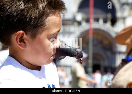Boy feeding pigeons en plein air sur la place San Marco, Venise Italie