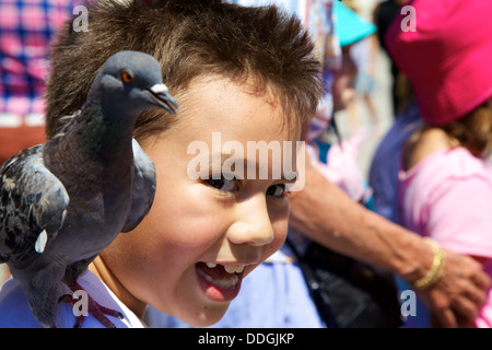 Boy feeding pigeons en plein air sur la place San Marco, Venise Italie