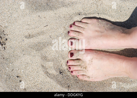 Les femmes pieds sur une plage de sable avec des ongles peints Banque D'Images