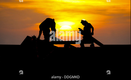 Les silhouettes des deux constructeurs construction contre un beau coucher du soleil Banque D'Images