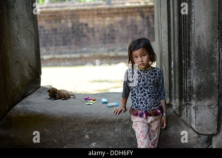 Temple d'Angkor Wat, Siem Reap, Cambodge - 01 Avril 2013 : une fille taciturne et chiot jouant sur le temple. Banque D'Images