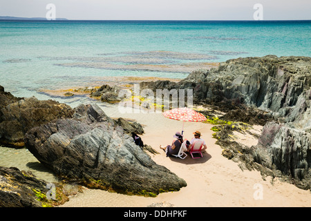 Couple assis sur la plage de Masua Banque D'Images