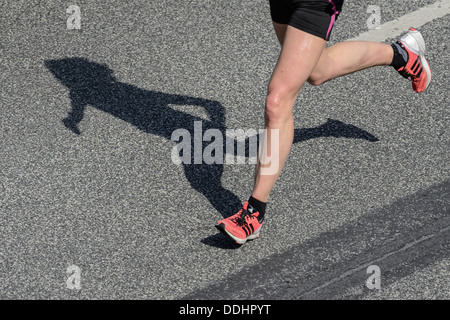 Les jambes et l'ombre d'un coureur de marathon Banque D'Images
