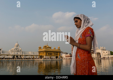 Un dévot Sikh prière à la sainte extérieure de l'Harmandir Sahib ou temple d'Or, un temple Sikh saint Banque D'Images