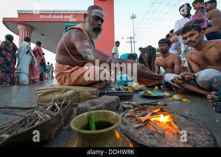 Prêtre hindou avec les pèlerins effectuant un rituel du feu à l'Agni Theertham Ghat Banque D'Images