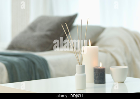 Aromatheraphy, bougies et encens sur table avec lit double en arrière-plan Banque D'Images