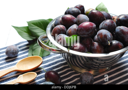 Prunes fraîches dans bol en métal sur fond de bois Banque D'Images