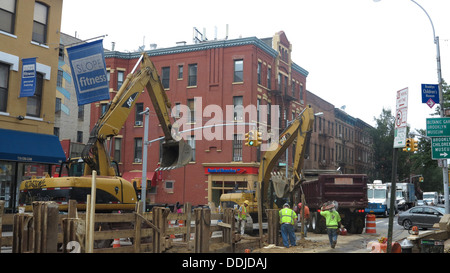 Mettre les travailleurs dans les nouveaux tuyaux sous la rue sur la 7e Avenue à Park Slope, Brooklyn, New York. Banque D'Images