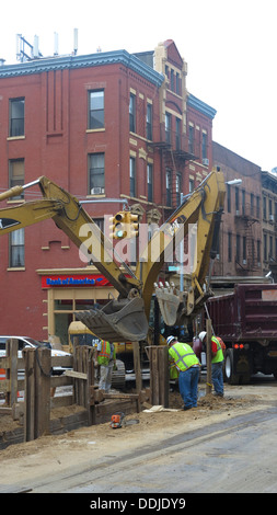 Mettre les travailleurs dans les nouveaux tuyaux sous la rue sur la 7e Avenue à Park Slope, Brooklyn, New York. Banque D'Images