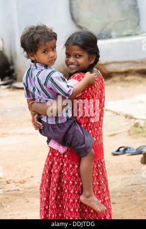 Smiling happy girl village portant son frère. L'Andhra Pradesh, Inde Banque D'Images