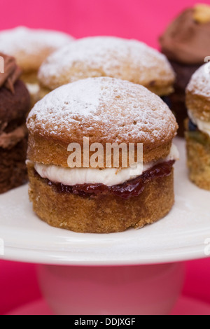 Une sélection de gâteaux faits maison mini sandwich Victoria sur fond rose. Banque D'Images