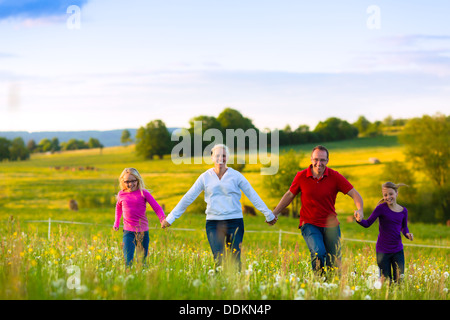 Famille heureuse avec filles marcher dans la prairie d'été Banque D'Images