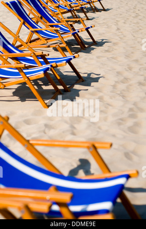 Le bleu et blanc à rayures transats sur une plage de sable vide Banque D'Images
