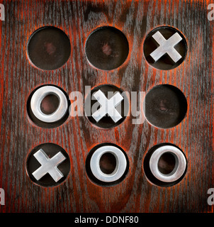 Jeu de morpion ou Tic Tac Toe et croix sur une planche en bois avec des pièces métalliques Banque D'Images