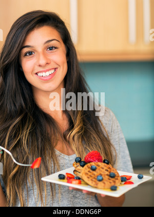 Young woman eating gaufres aux fruits frais, petit déjeuner à la maison Banque D'Images