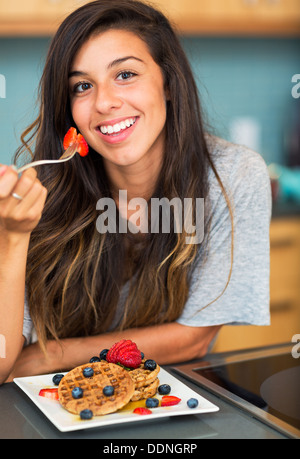 Young woman eating gaufres aux fruits frais, petit déjeuner à la maison Banque D'Images