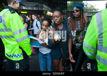 Une femme demande de sens que deux jeunes filles noires avec une bouteille ofwhiskey dans leurs mains pousser leur chemin à travers les lignes de police. Banque D'Images